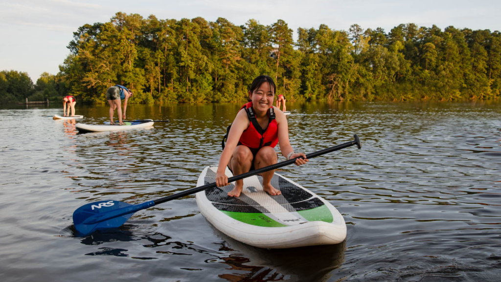 A student paddle boards on Lake Raleigh. 
