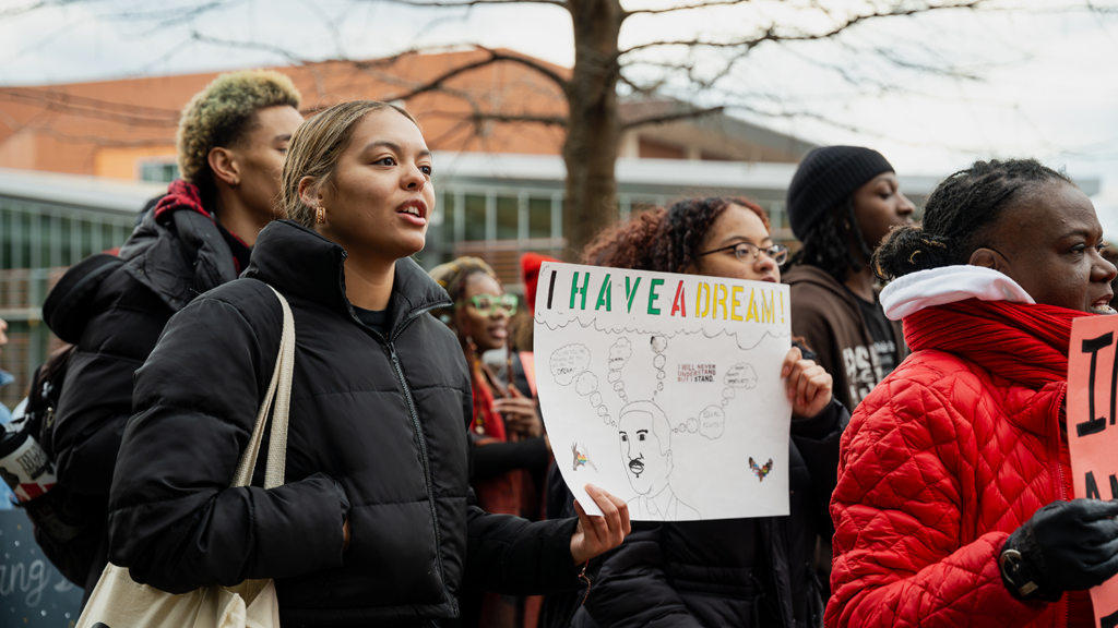 Students with signs march through main campus.