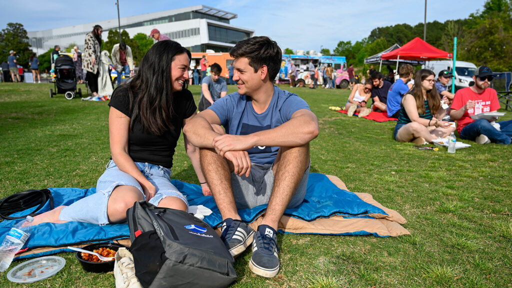Students relax on the lawn at Lake Raleigh.