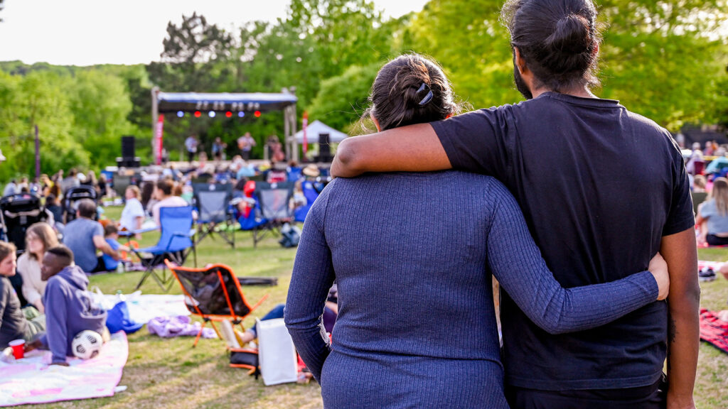 Audience members stand arm in arm during a LIVE@Lake Raleigh concert.