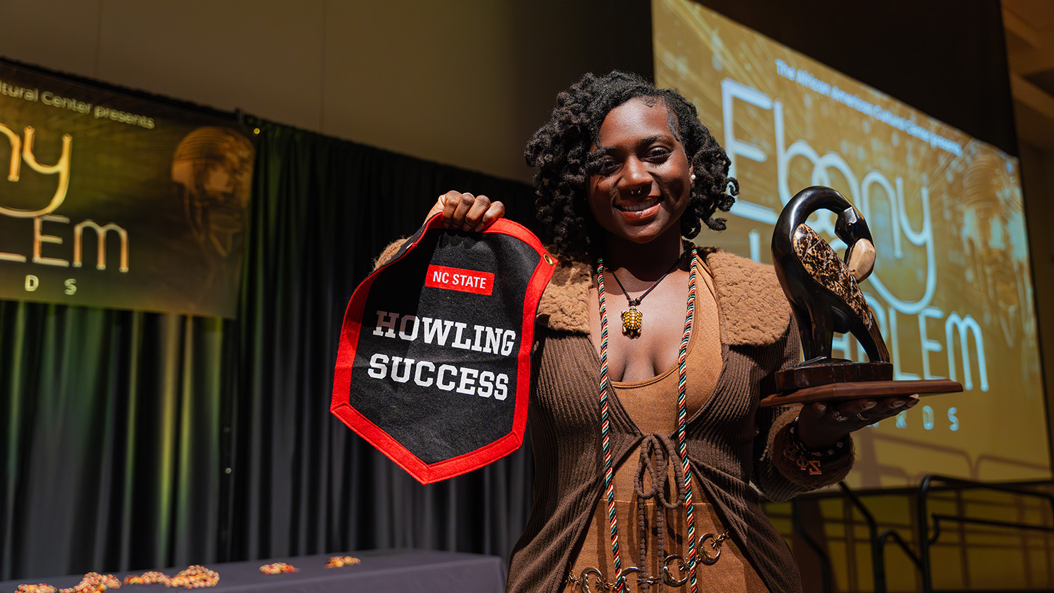 Shaniya Woolridge proudly displays their Howling Success banner and Ebony Harlem Award.