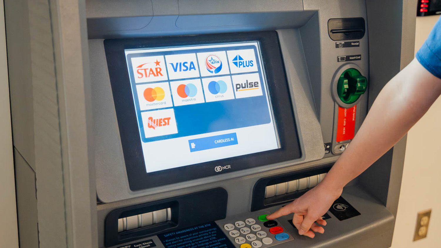 A student presses a button an ATM machine.