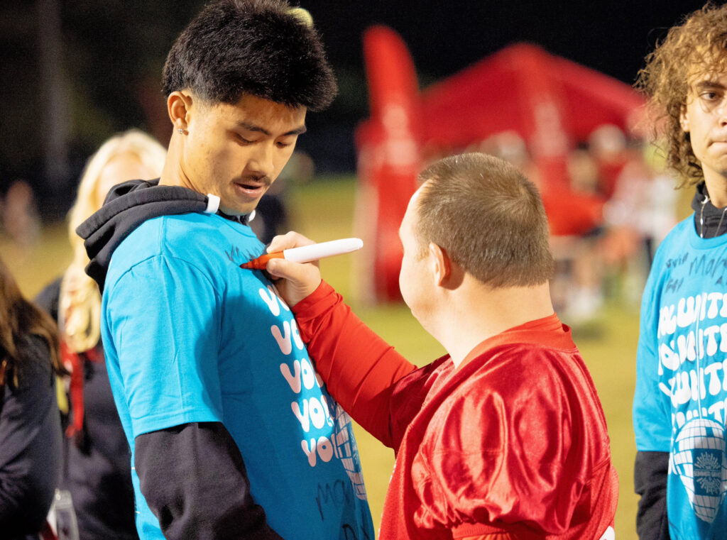 A Special Olympics athlete signs an NC State student's shirt.
