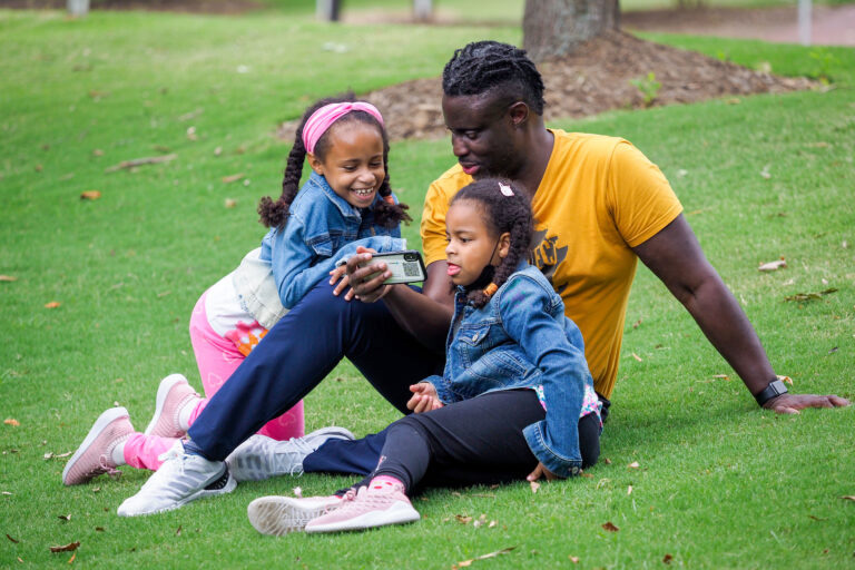 A family relaxes on the Gregg Museum front lawn.