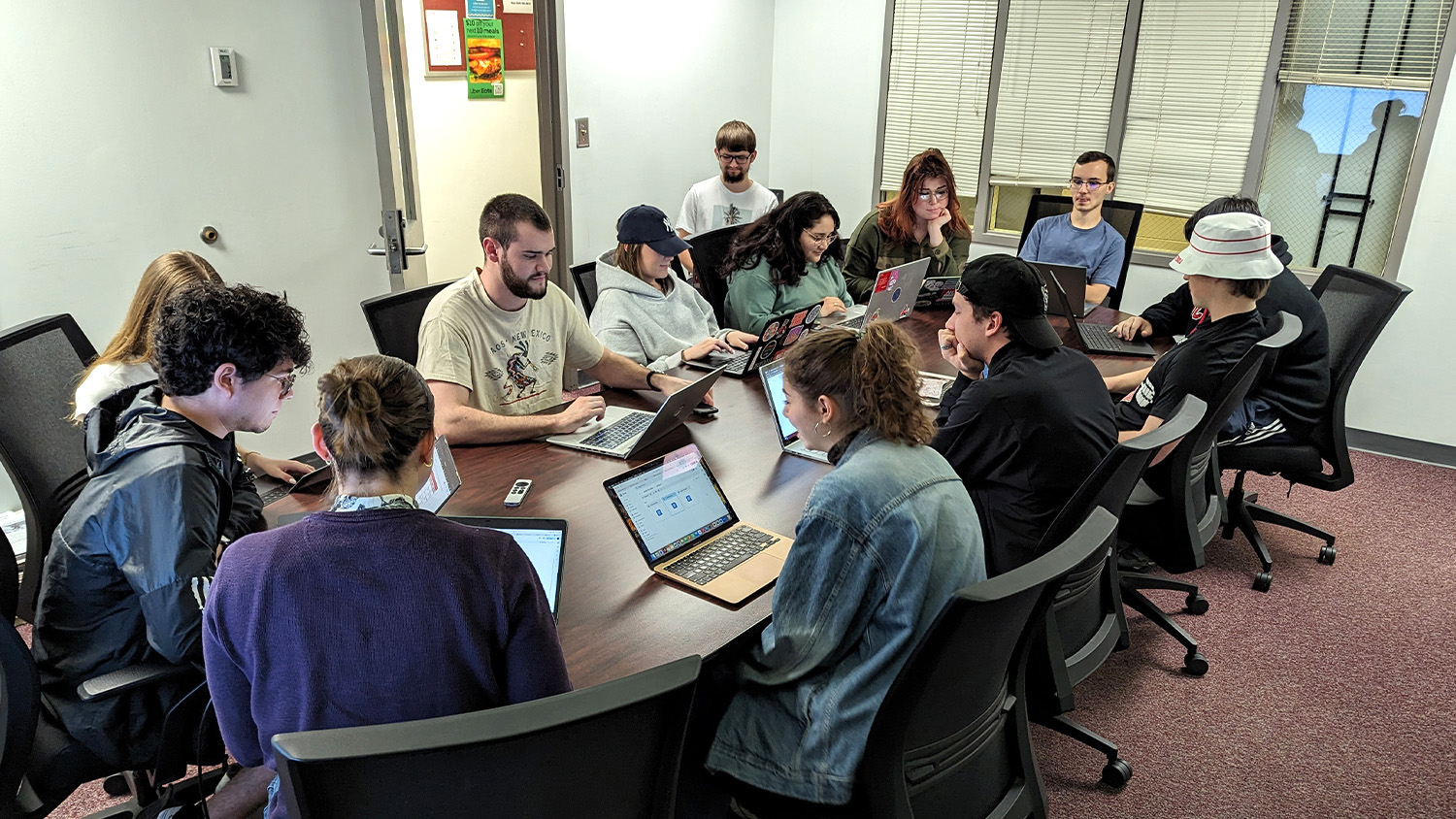 Student media students gather around a conference room table.